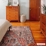 Bedroom scene with a red, beige, and blue Neyland Area Rug, wood floors, and mid-century modern furniture. Roomscene-Rectangle