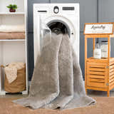 Laundry room scene with a light gray Judy Solid Washable Shag Rug coming out of the washing machine. Washing-Machine