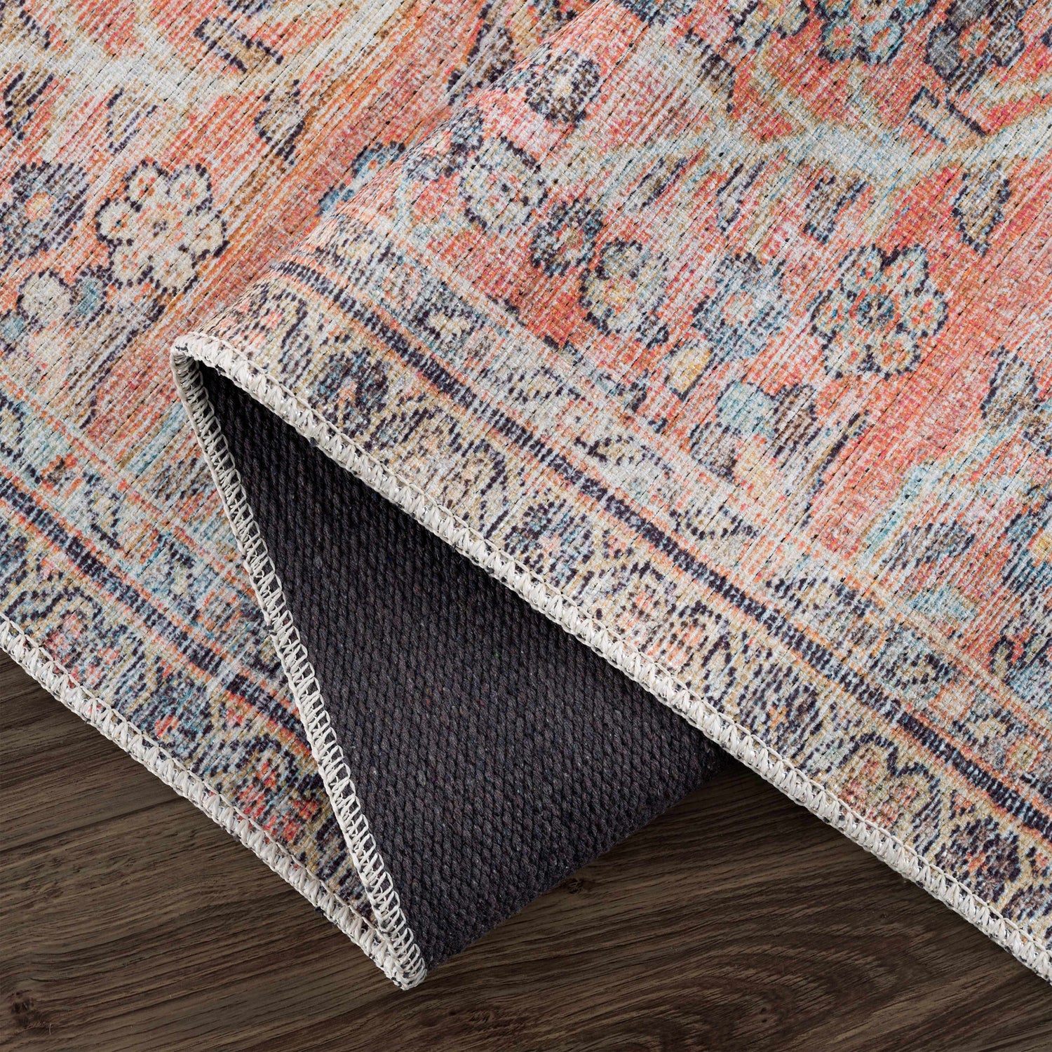 Close-up of the Urpi Rose & Blue Washable Area Rug showing its traditional Persian pattern and colors of rose, blue, and beige. Fold
