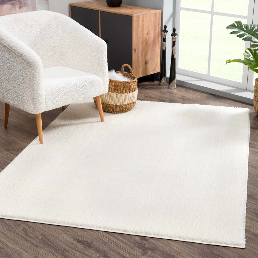 Living room scene with a Judy White Washable Area Rug, fluffy white chair, wood cabinet, and dark wood floors. Roomscene-Rectangle