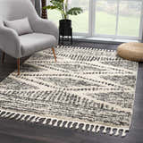 Living room scene with a gray chair and the Fishhook Berber Shag Rug in dark gray and lambswool with tassels. Roomscene-Rectangle