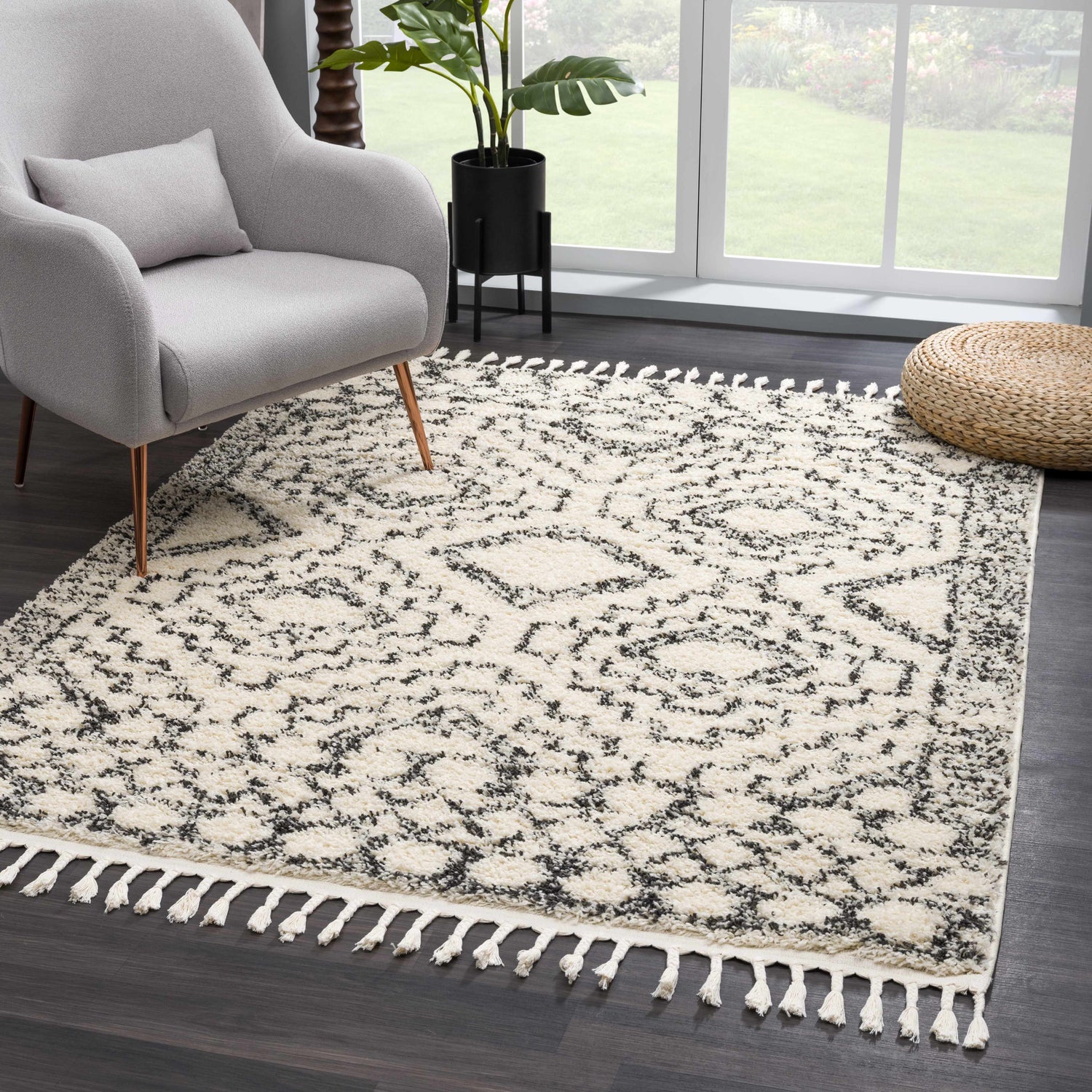 Living room scene with a gray chair and the Buan Area Rug, a shag rug with a gray Moroccan pattern and tassels. Roomscene-Rectangle