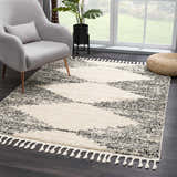 Living room scene with a gray chair and the bone and dark gray Howth Area Rug with tassels. Roomscene-Rectangle