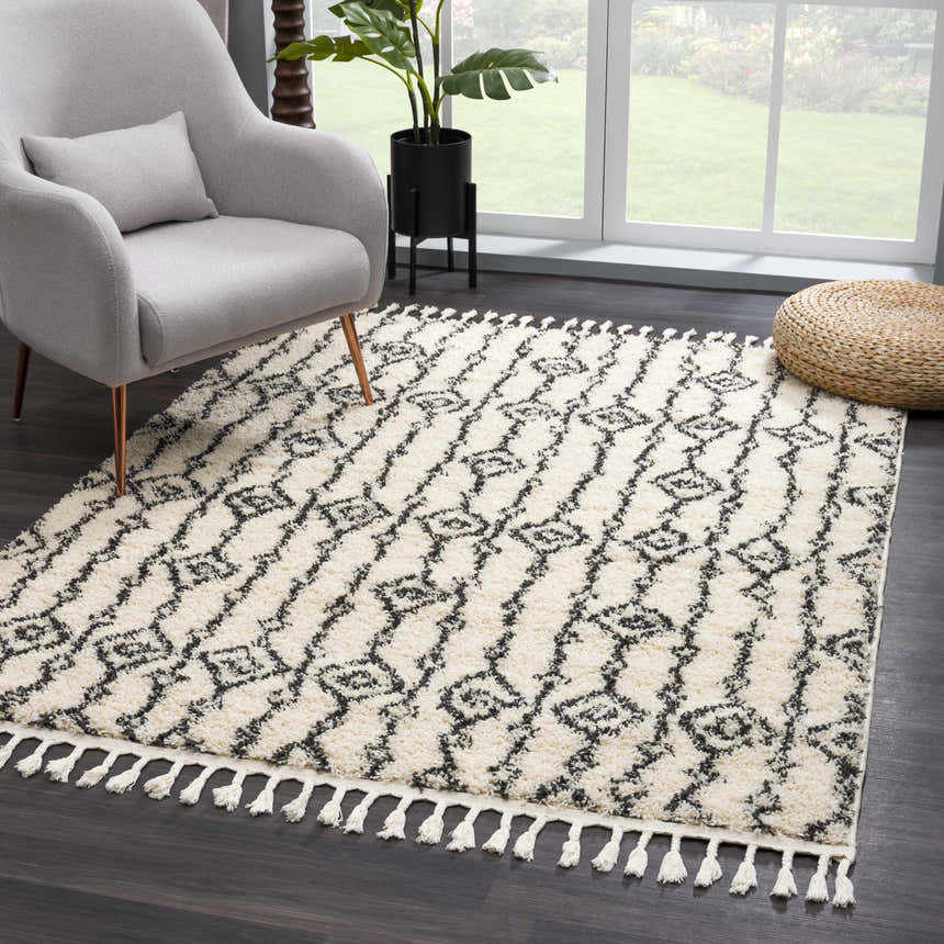 Living room scene with a Bayanga area rug in charcoal and white, gray chair, and natural light. Roomscene-Rectangle