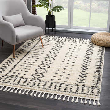 Living room scene with gray chair and Hauppauge Berber Shag Carpet in charcoal and light beige with tassels. Roomscene-Rectangle