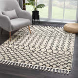 Living room scene with a charcoal and light beige Muni Berber Shag Rug, gray chair, and woven ottoman. Roomscene-Rectangle