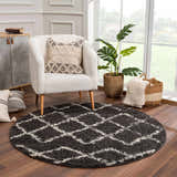 Living room scene with round Wallagrass Black Moroccan Shag Rug, white chair, wood floors, and natural light from a large window. Roomscene-Round
