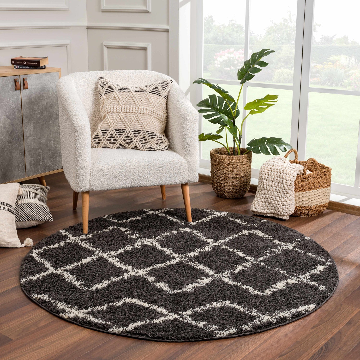 Living room scene with round Wallagrass Black Moroccan Shag Rug, white chair, wood floors, and natural light from a large window. Roomscene-Round