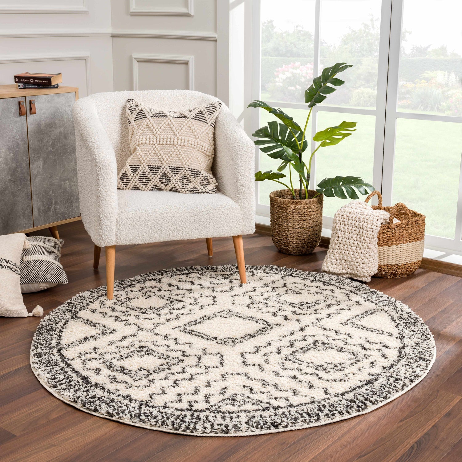 Cozy living room scene with round Buan Area Rug in charcoal and cream, textured chair, and natural light. Roomscene-Round