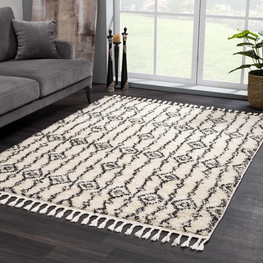 Living room scene with a gray sofa and the Bayanga rug in charcoal and cream with a Moroccan shag design. Roomscene-Rectangle