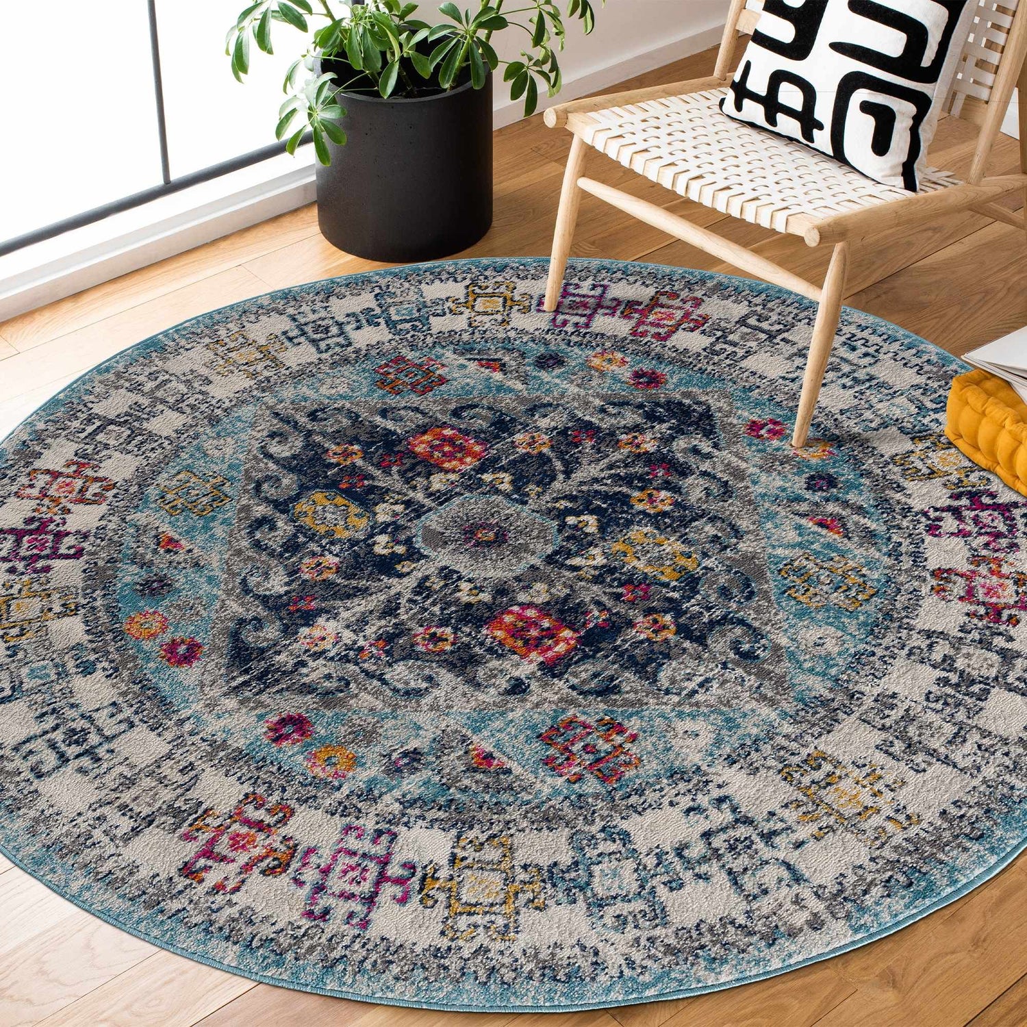 Round Tigris Turquoise 2314 rug in a bright room with wood floors, chair, and plant. Bohemian style with blue, ivory, and pink accents. Roomscene-Round