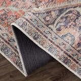 Close-up of the Konstantina Washable Area Rug showing its vintage Persian design, aqua, beige, and brown colors, and non-slip backing. Fold