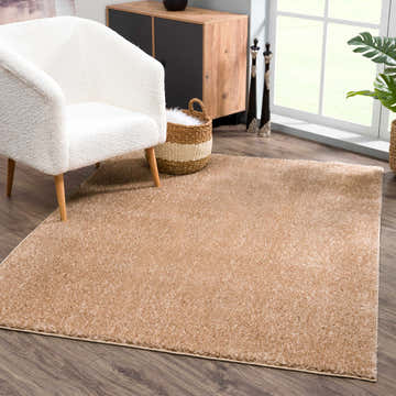 Living room scene with a Judy Brown Promo Washable Area Rug, cream chair, wood cabinet, and dark wood floors. Roomscene-Rectangle