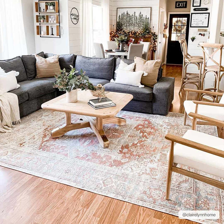 Living room scene with a gray sectional, wood furniture, and the Rust Maayon Washable Rug in brick red and brown tones. Roomscene-Rectangle