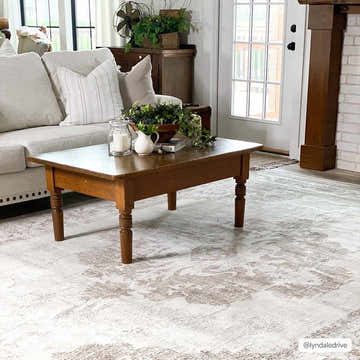 Living room scene with a gray sofa and the light tan Benkelman Area Rug under a wooden coffee table. Roomscene-Rectangle
