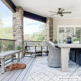 Outdoor patio scene with a Marwood Nordic Performance Rug, gray furniture, stone pillars, and a sleeping dog. Styleshot