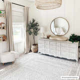Neutral nursery with Burdette Soft Neutral Rug, white dresser, round mirror, and sheep ottoman. Calm, cozy vibe. Roomscene-Rectangle