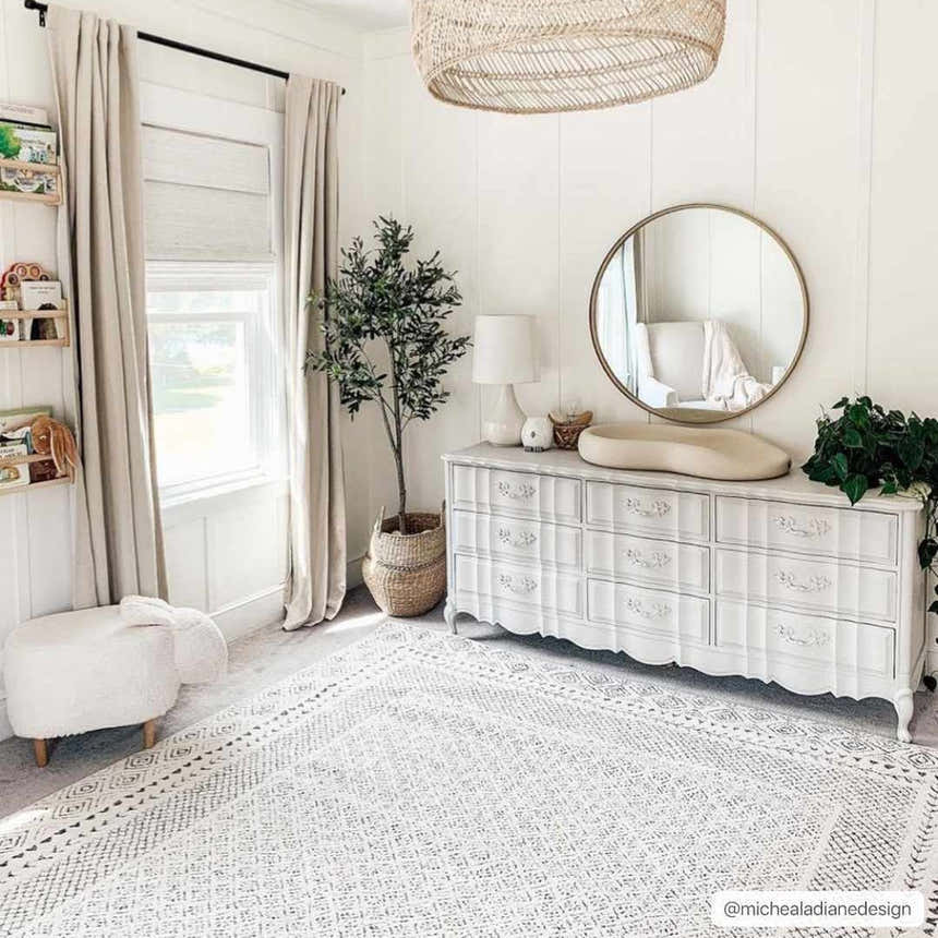 Neutral nursery with Burdette Soft Neutral Rug, white dresser, round mirror, and sheep ottoman. Calm, cozy vibe. Roomscene-Rectangle