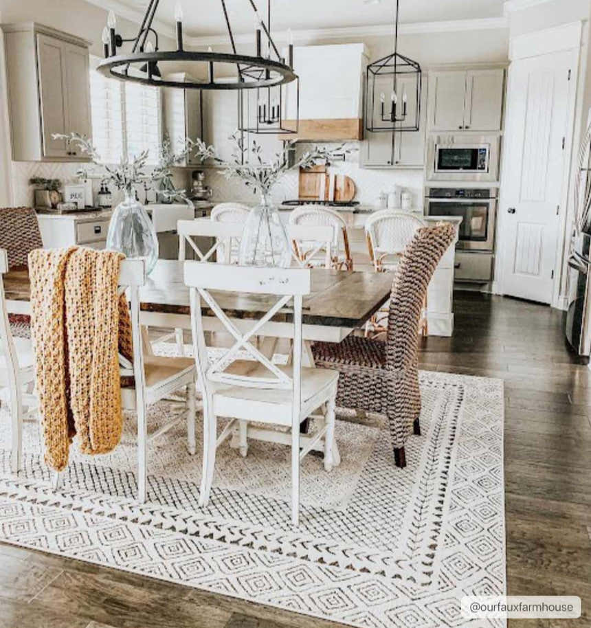 Farmhouse dining room with a Burdette Soft Neutral Rug under a wood table and white chairs. Gray cabinets in background. Roomscene-Rectangle
