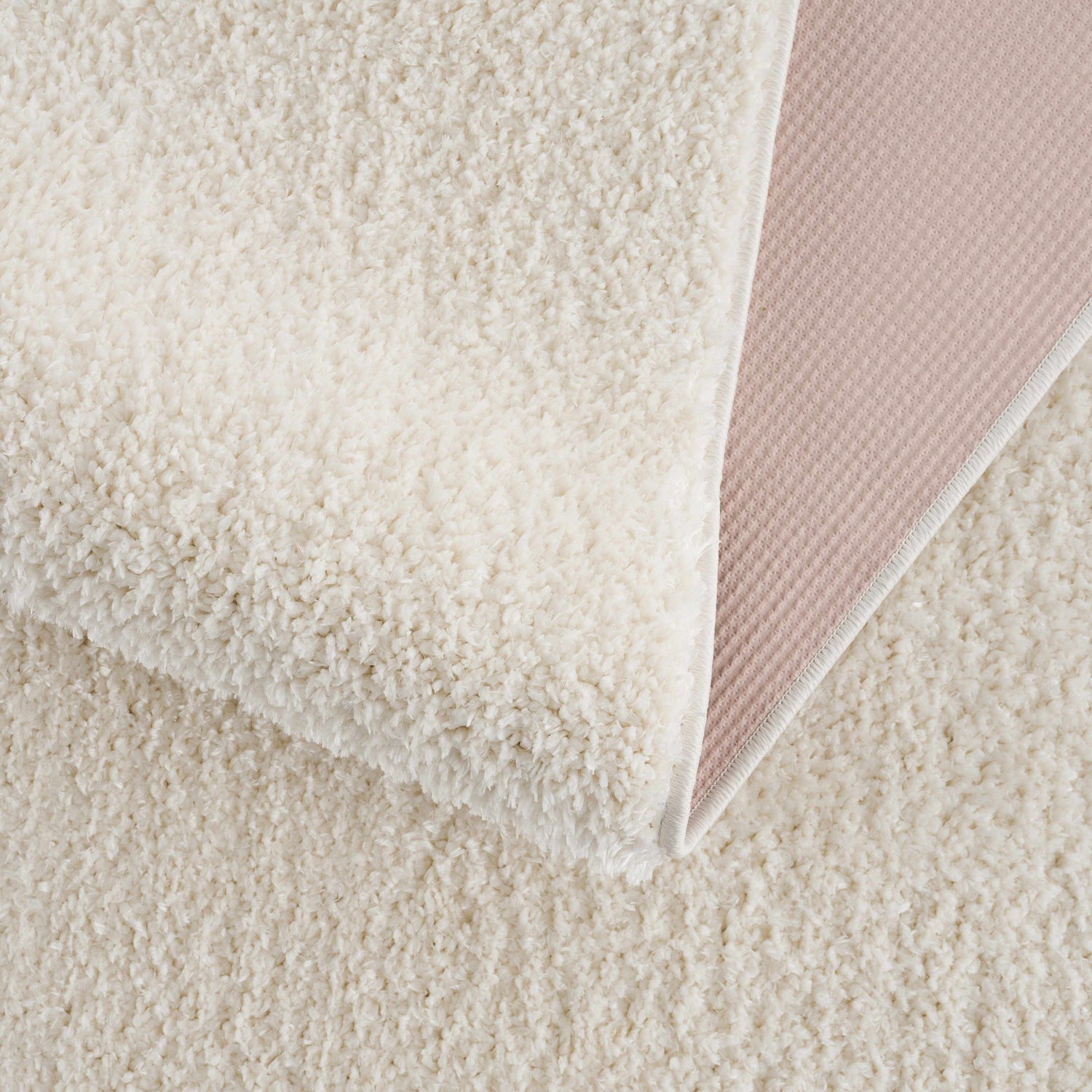 Close up of the Judy White Washable Area Rug showing its plush shag texture and non-slip backing. Fold