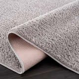 Close-up of the Judy Solid Gray Washable Shag Rug showing its plush texture and durable backing on dark wood floors. Fold