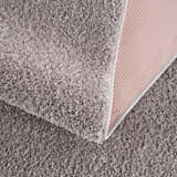 Close-up of the plush texture and backing of the Judy Solid Gray Washable Shag Rug. Fold