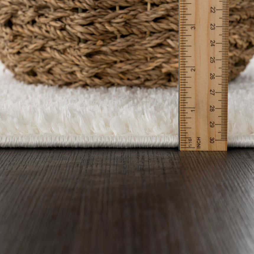 Close-up of the Judy White Washable Area Rug showing its plush texture and thickness with a ruler and basket for scale. Pile