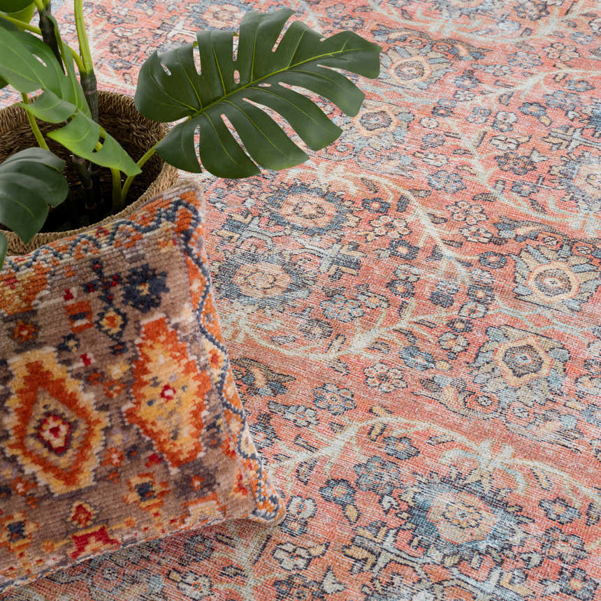 Close-up of the Urpi Rose & Blue Washable Area Rug featuring a traditional Persian pattern and a plant in a basket. Styleshot