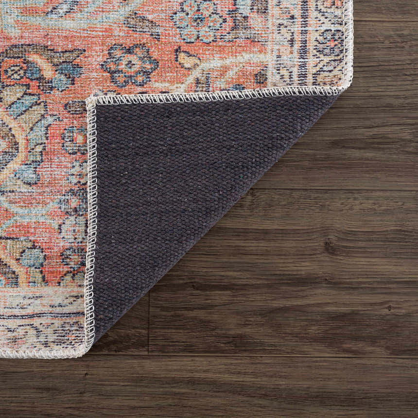 Close-up of Urpi Rose & Blue Washable Area Rug showing Persian-style design, rose, blue, and cream colors, and non-slip backing. Fold