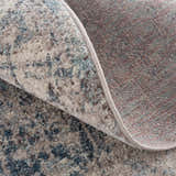 Close-up of the Orrick Area Rug showing the blue, cream, and brown abstract pattern and woven texture. Fold
