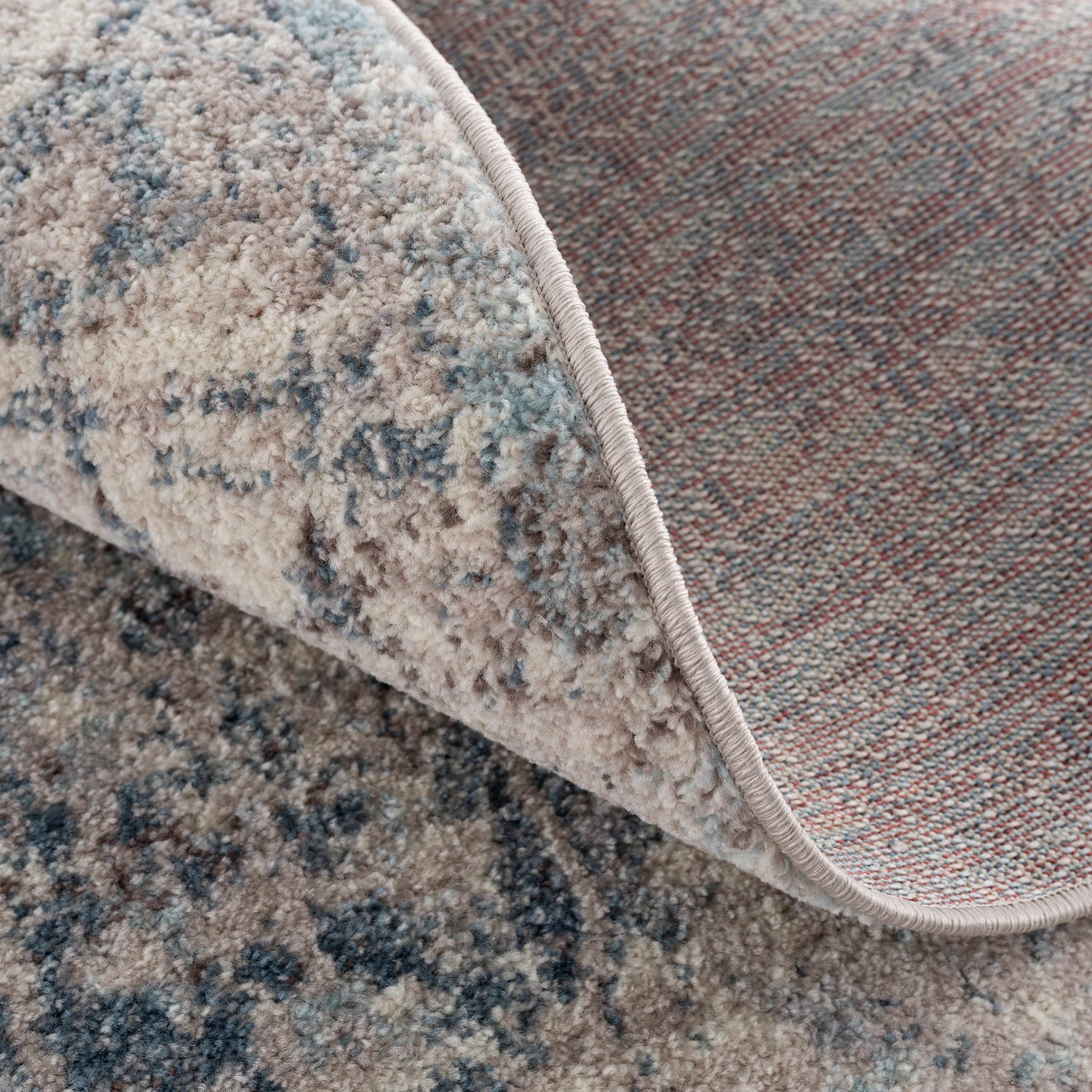 Close-up of the Orrick Area Rug showing the blue, cream, and brown abstract pattern and woven texture. Fold