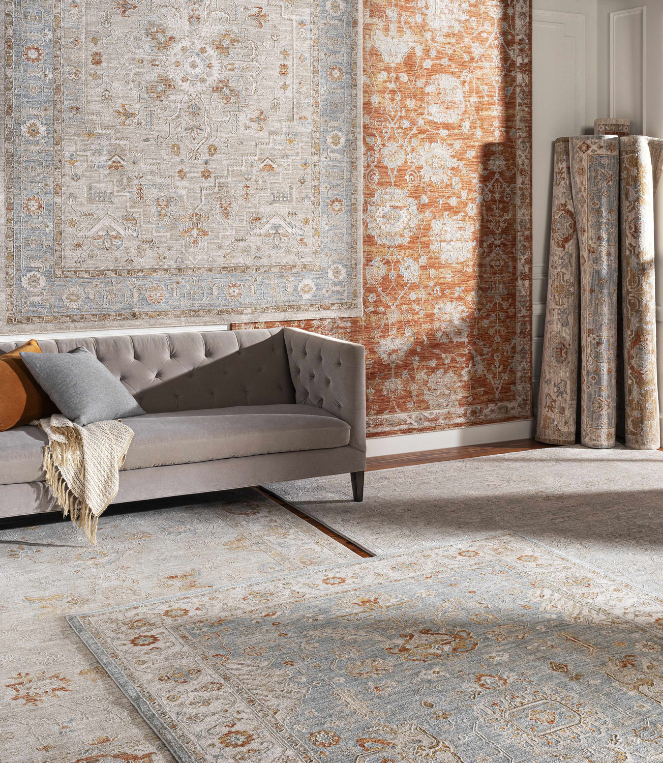 Living room scene with a Phyllis Thick Luxe Statement Rug in light beige and blue, styled with a gray sofa. Styleshot