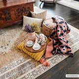 Cozy living room scene with a brown and light blue Albas Washable Area Rug, pillows, tea set, and blanket. Roomscene-Rectangle