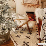 Cozy Christmas living room with Alstead Shag Area Rug, fireplace, faux fur chair, and decorated tree. Roomscene-Rectangle
