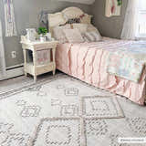 Light and airy bedroom with pink bedding and the Amaga High-Low Rustic Rug in cream and charcoal. Roomscene-Rectangle