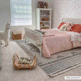 Kids bedroom with a white bed on the Amaga High-Low Rustic Rug in charcoal, cream, and beige tones. Roomscene-Rectangle