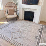 Living room scene with a Bohemian style Amaga High-Low Rustic Rug in cream and gray, egg chair, and fireplace. Roomscene-Rectangle