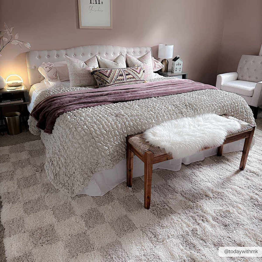 Bedroom scene with the Atira Light Brown Checkered Area Rug. Pink walls, white bedding, and a cozy, inviting mood. Roomscene-Rectangle