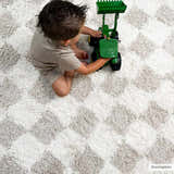 Kids room scene with a child playing on the Atira Light Brown Checkered Area Rug. Cream and light brown shag rug. Fold