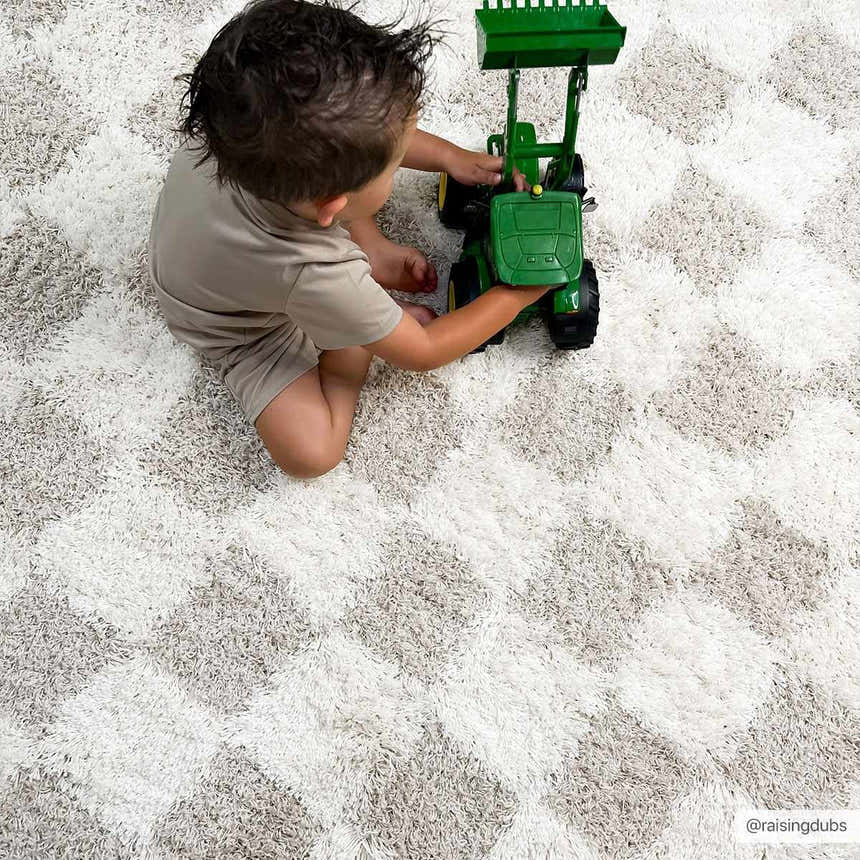 Kids room scene with a child playing on the Atira Light Brown Checkered Area Rug. Cream and light brown shag rug. Fold