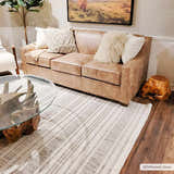 Living room scene with a beige leather sofa and the striped beige Avari Area Rug. Roomscene-Rectangle