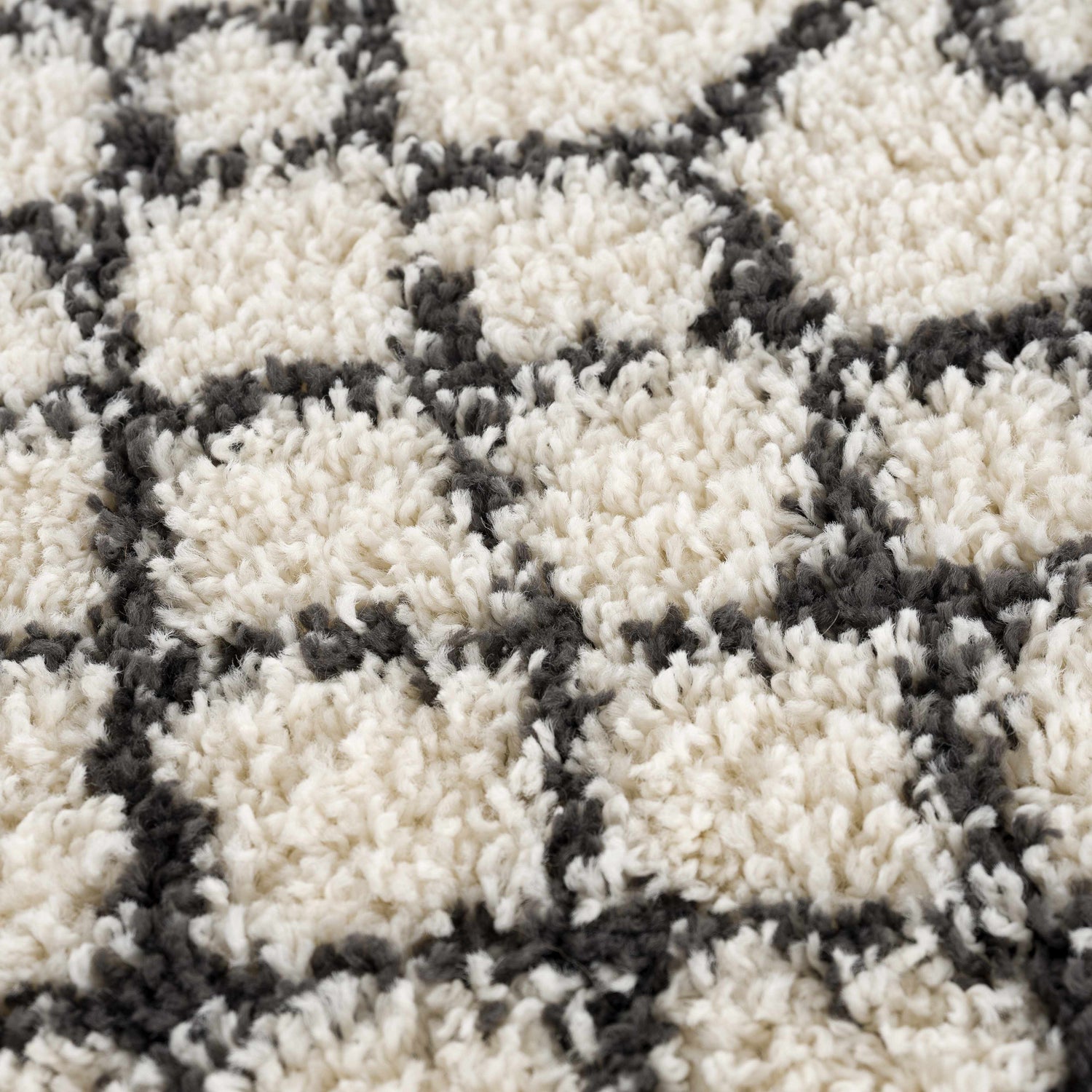 Close-up of the Muni Berber Shag Rug, featuring a charcoal geometric pattern on a light beige, high-pile shag texture. Texture