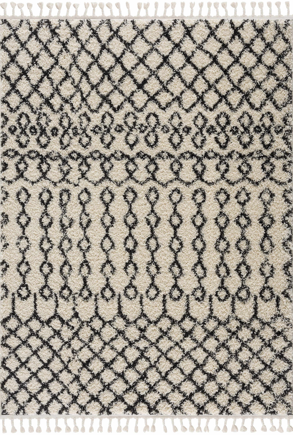 Close-up of the Muni Berber Shag Rug. Features a charcoal and light beige Moroccan-inspired diamond pattern and tassels. Design-Rectangle-5373
