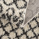 Close-up of the Muni Berber Shag Rug showing charcoal and light beige colors and shag texture. Machine woven construction detail. Fold