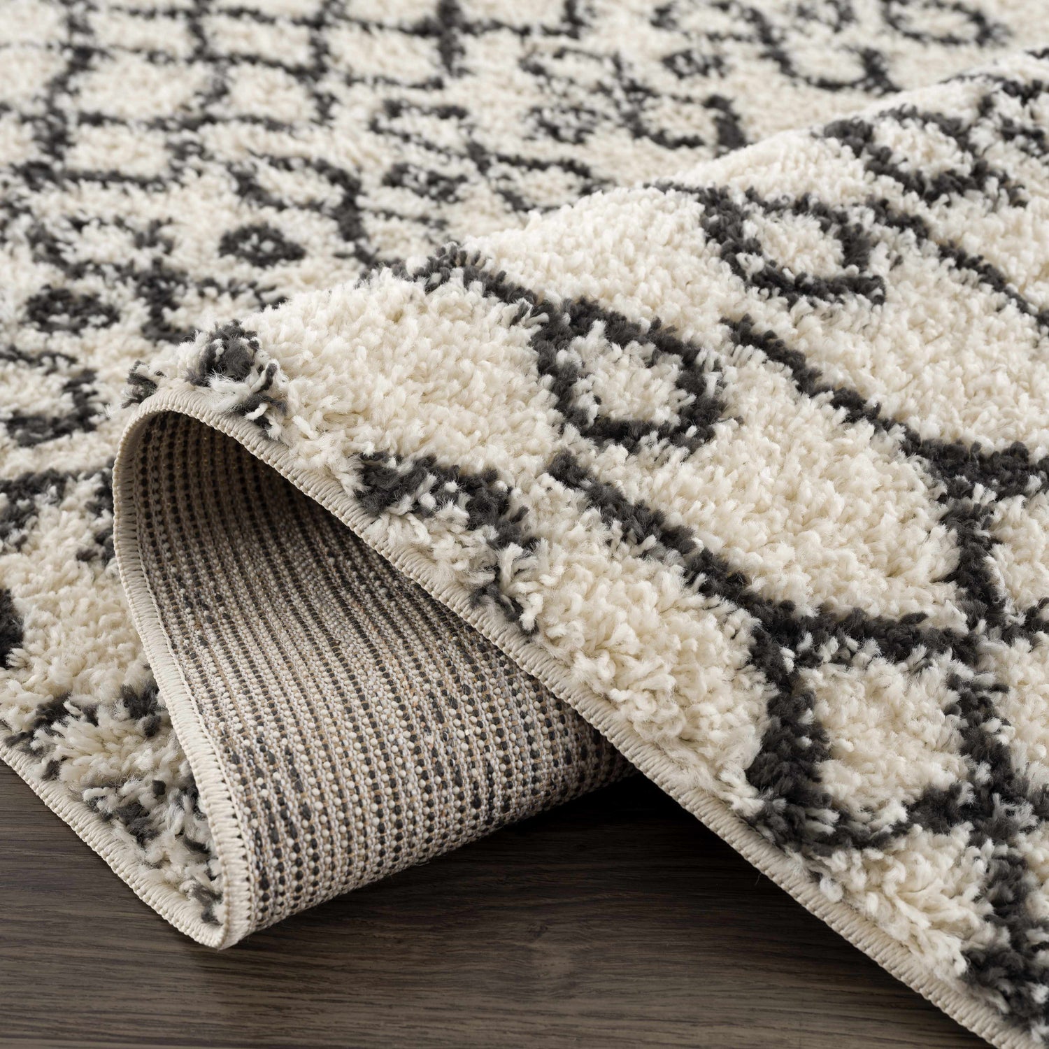 Close-up of the Muni Berber Shag Rug in charcoal and light beige, showing the shag texture and Moroccan-inspired pattern. Fold