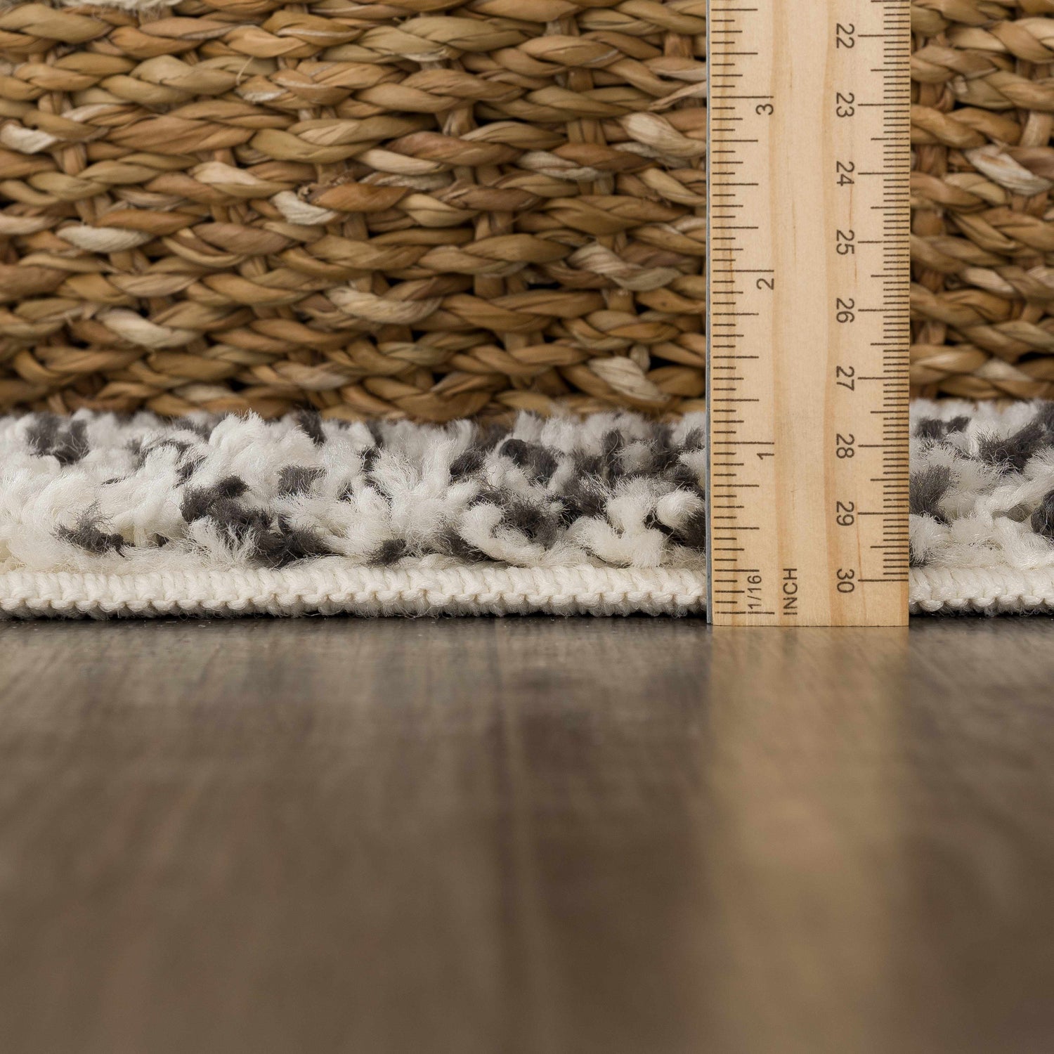 Close-up of Buan Area Rug showing shag texture, gray and white pattern, and pile height measured with a ruler. Pile