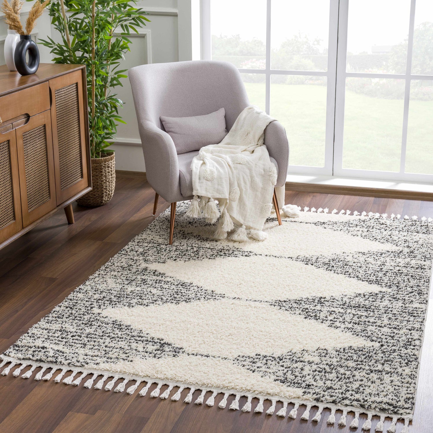 Living room scene with a bone and dark gray Howth Area Rug, gray chair, and wood cabinet. Roomscene-Rectangle