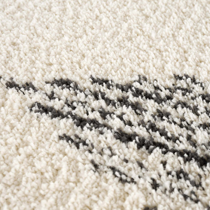 Close-up of the Howth Area Rug showing its bone and dark gray shag texture and Moroccan-inspired design. Texture