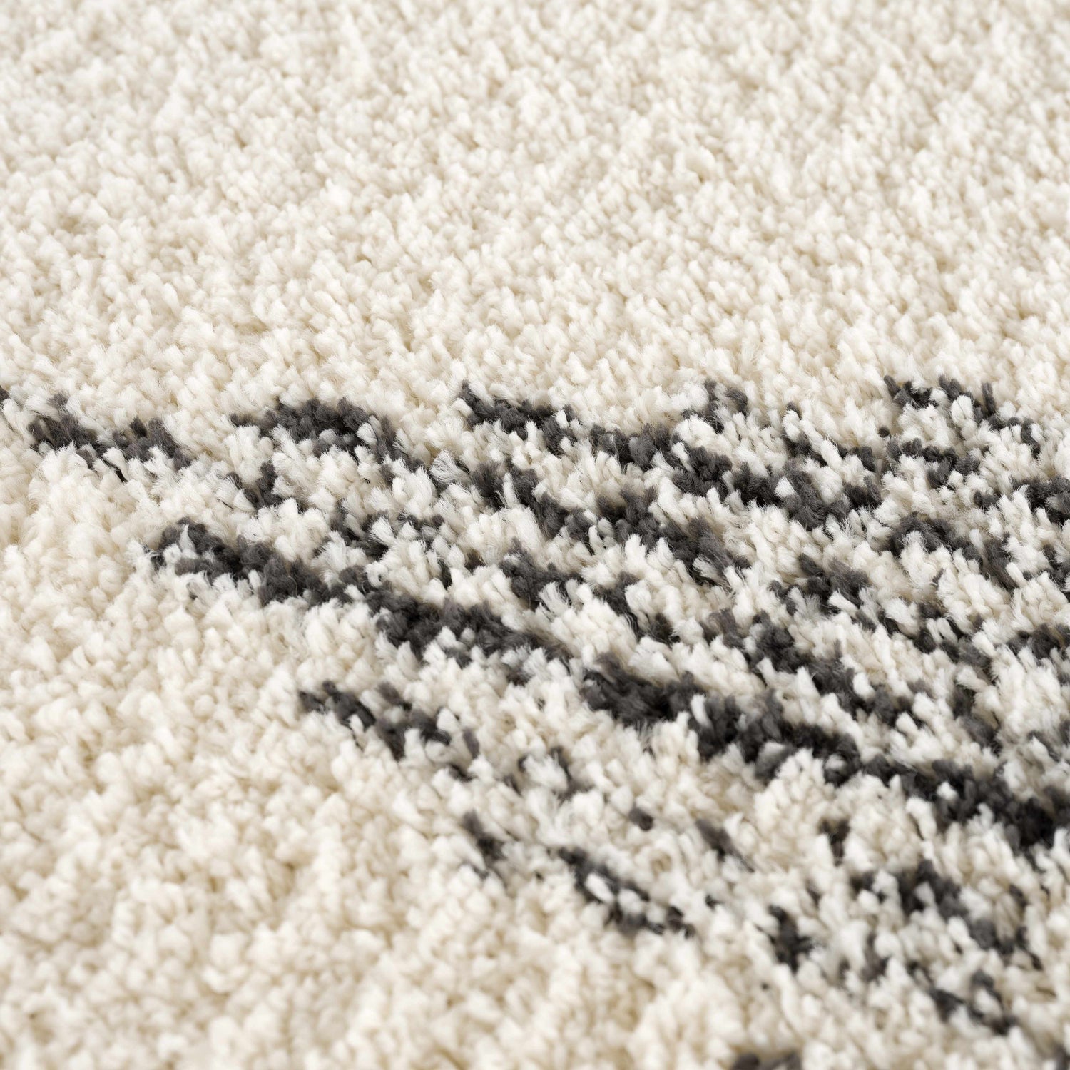 Close-up of the Howth Area Rug showing its bone and dark gray shag texture and Moroccan-inspired design. Texture