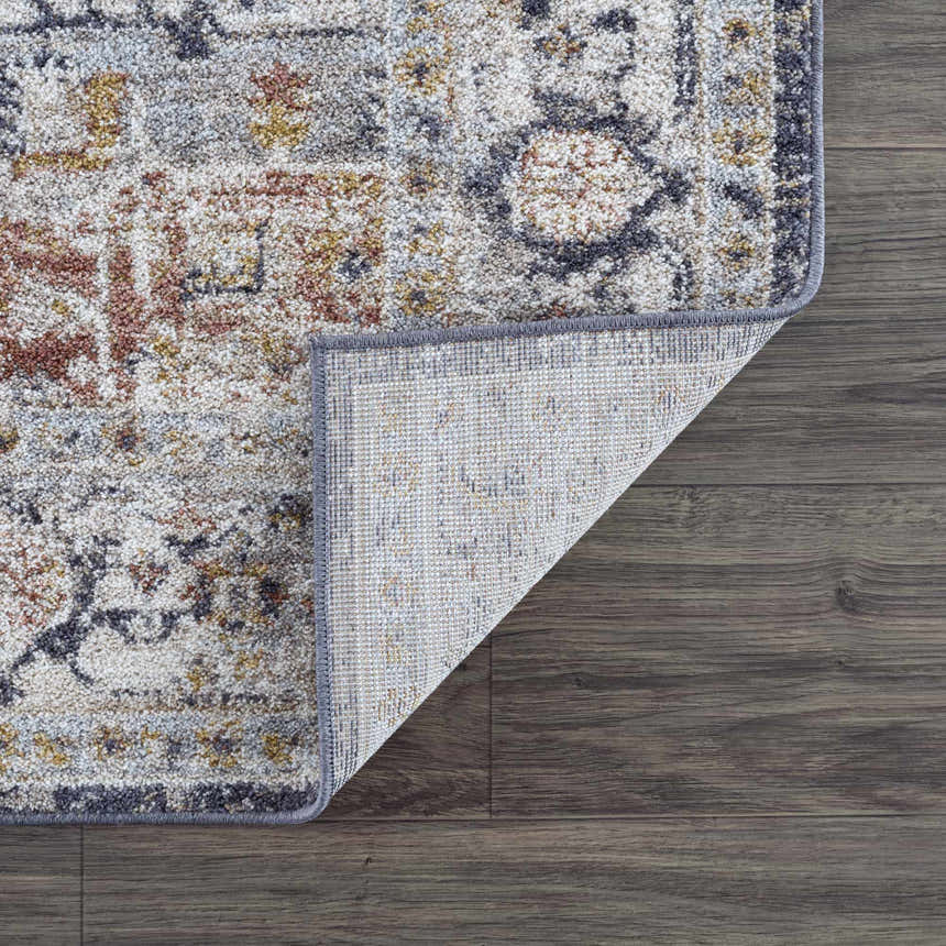 Close-up of the Ivria Navy & Rust Area Rug showing its traditional design, light gray, natural gray, navy, and rust colors. Fold